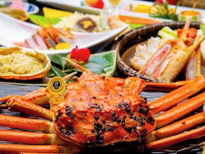 A crab with black peppercorns on a wooden table. - Awara Onsen Seifuso (Awara)