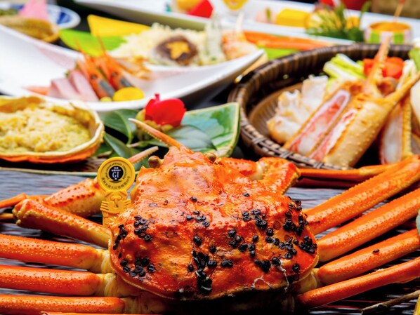 A crab with black peppercorns on a wooden table.