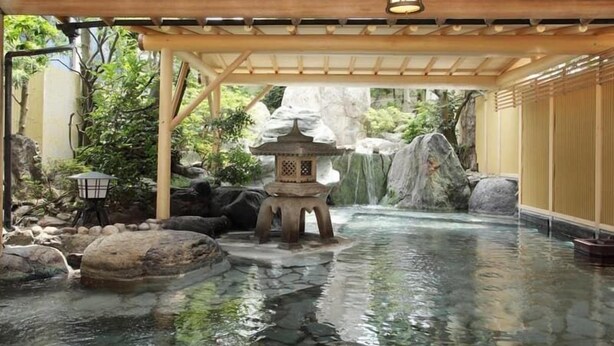 Um jardim japonês tradicional com um farol de pedra, uma pequena pagode e uma cascata.