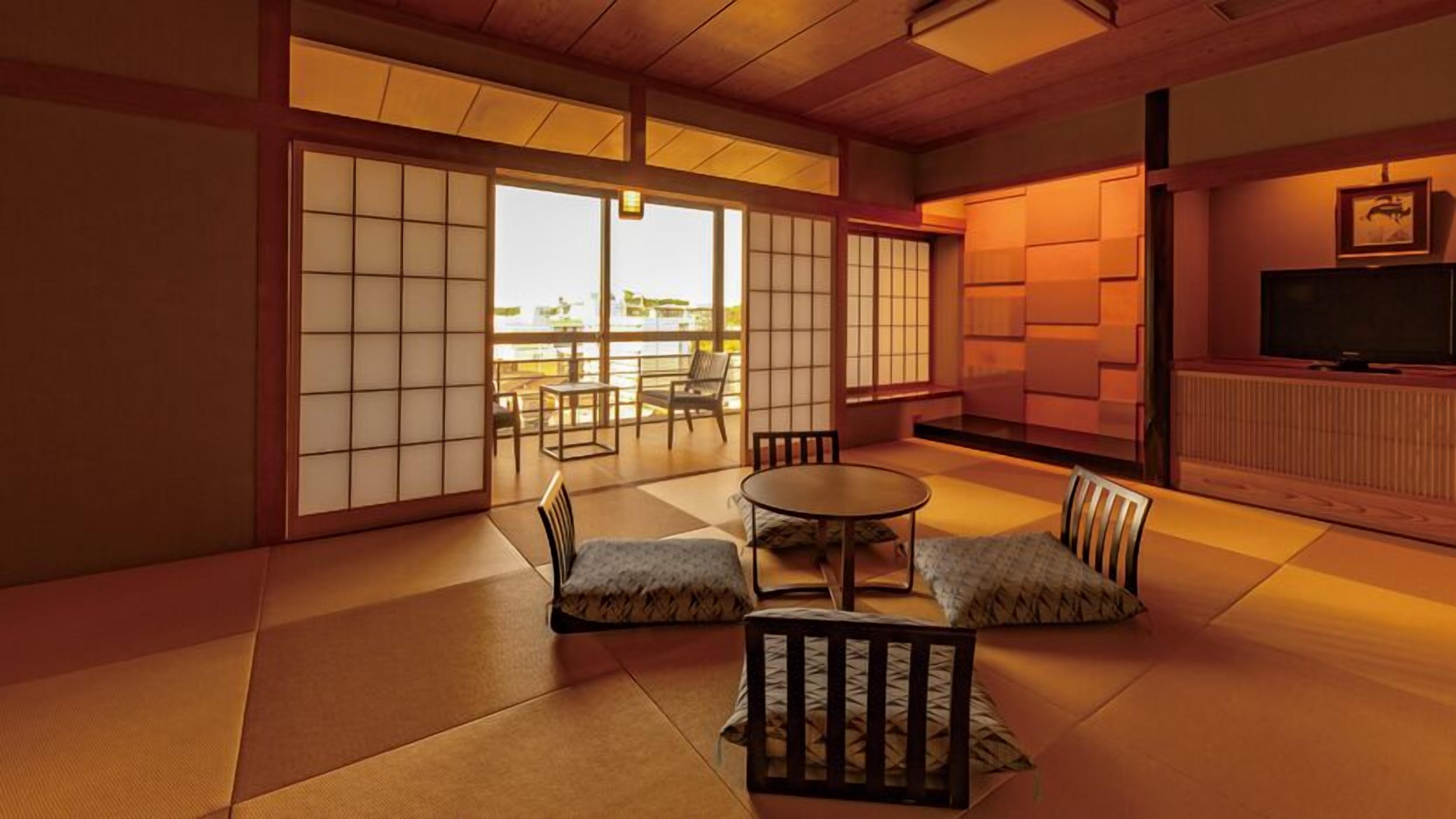 Una habitació tradicional japonesa amb terra de tatami, portes corredisses, una taula baixa amb coixins i una televisió.