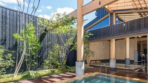Uma área de piscina moderna ao ar livre, com um deck de madeira, um espaço de estar coberto e um cercado de madeira.