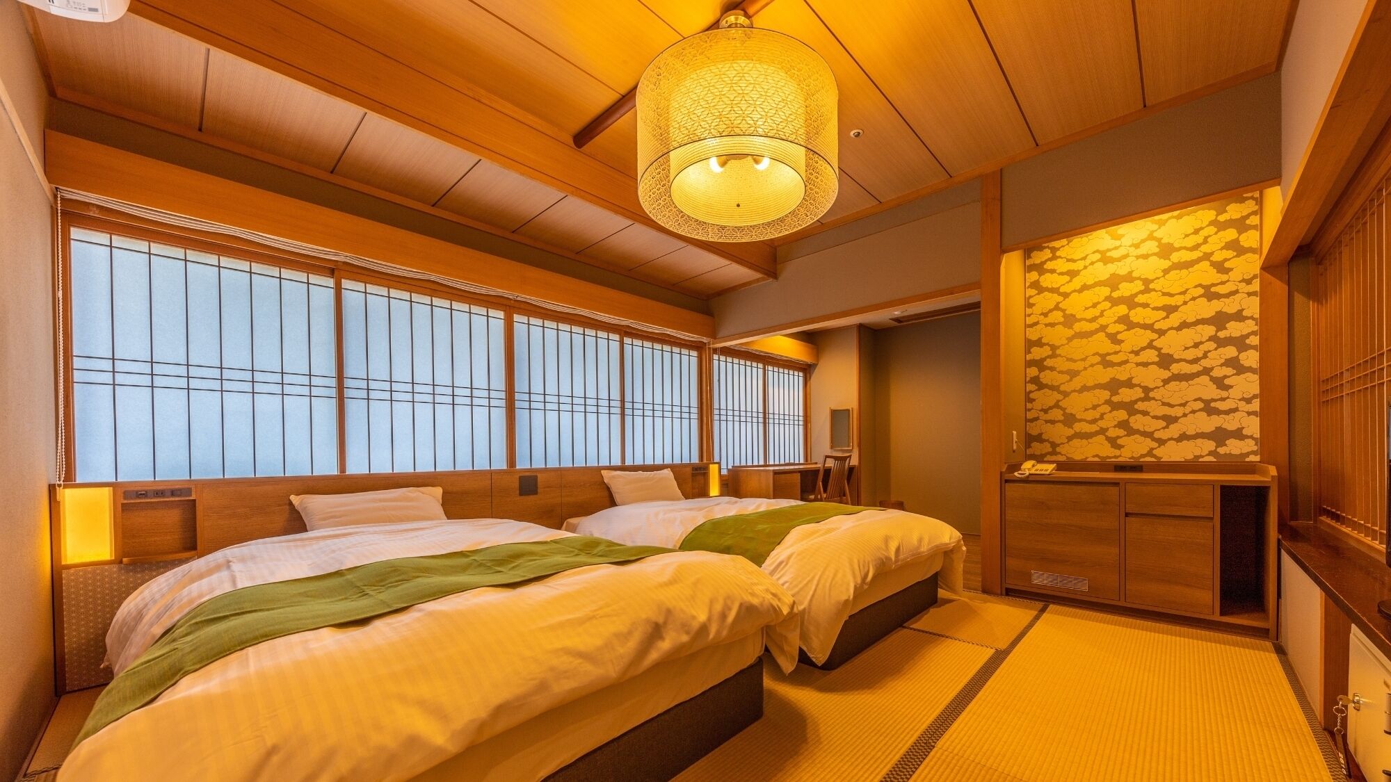Una habitación tradicional japonesa con suelo de tatami, pared de fusuma y una lámpara colgante.