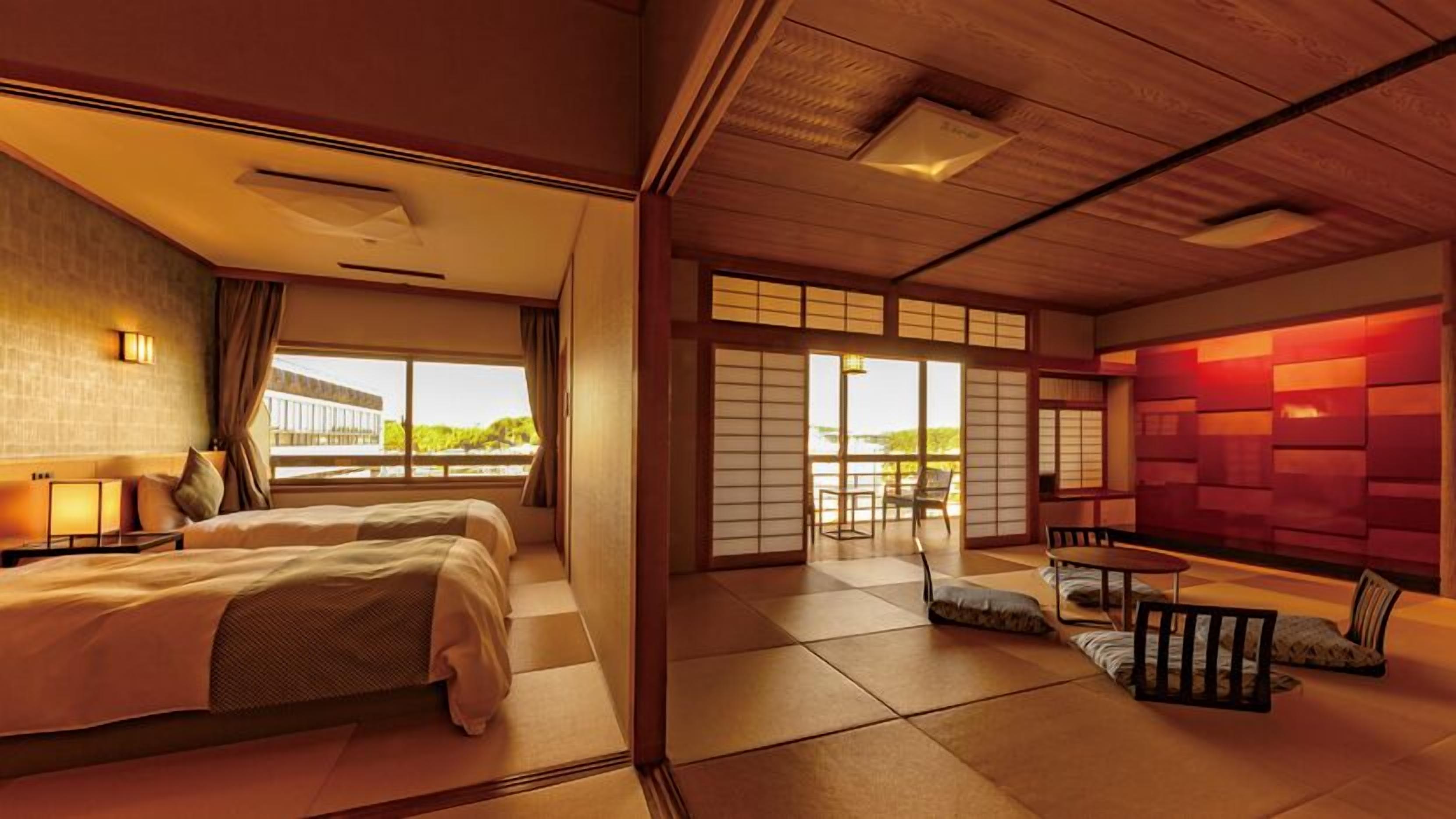 Habitación de hotel con cama, zona de estar con mesa y vistas a zonas verdes.