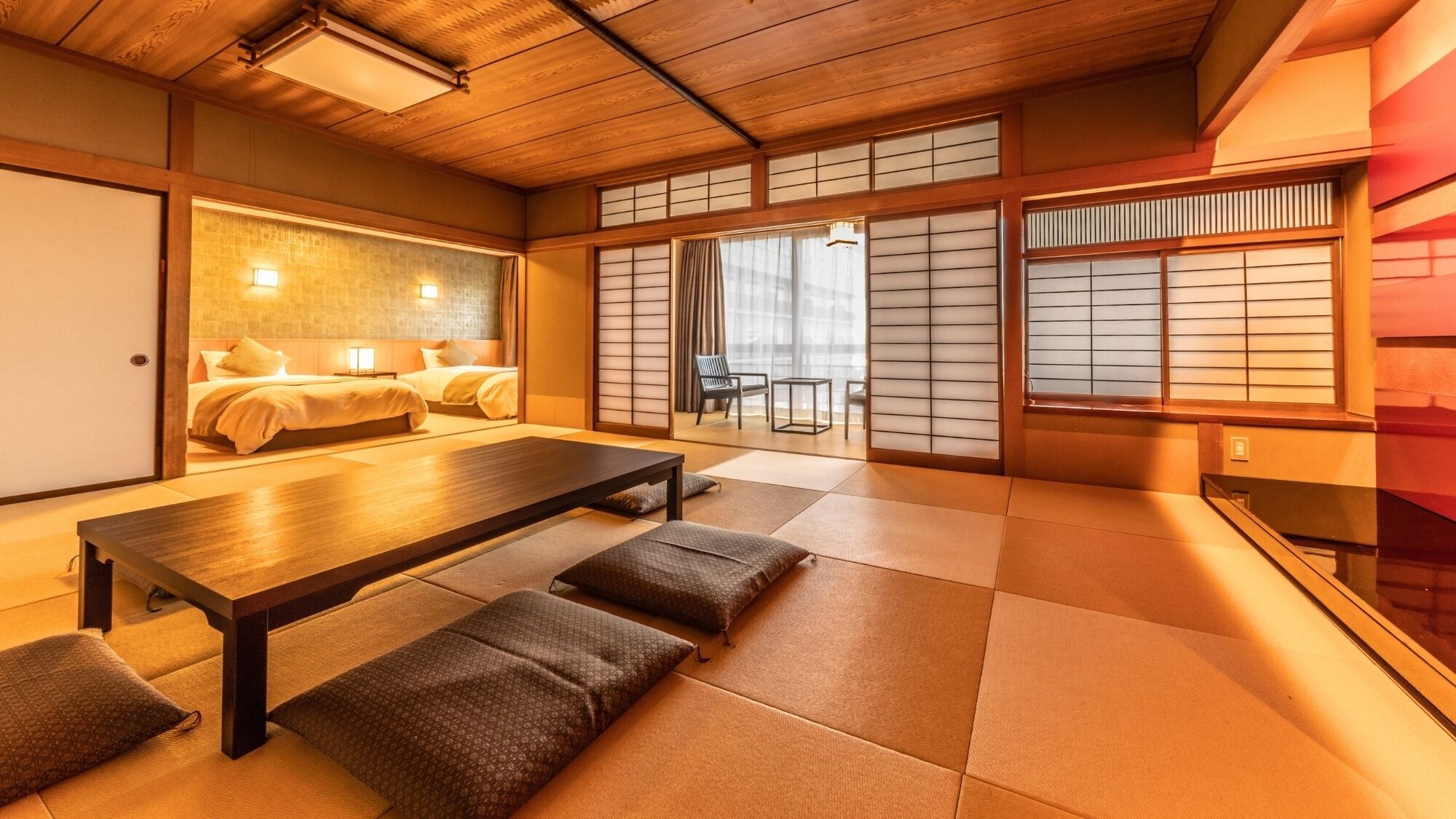 Una habitación tradicional japonesa con suelo de tatami, una mesa baja y puertas correderas.