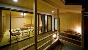 Uma cabana de madeira com varanda, hidromassagem e área de refeições com mesas e bancos.
