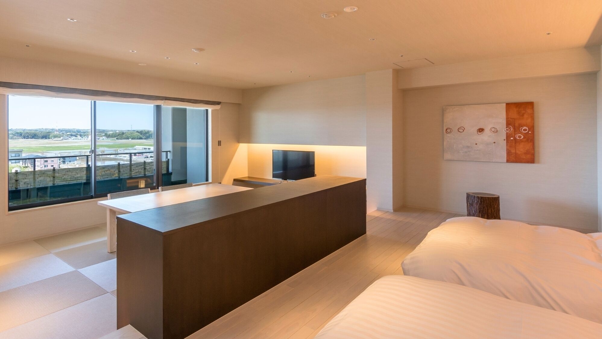 Habitación de hotel moderna con un ventanal grande, un televisor de pantalla plana, un escritorio de madera y una cama.