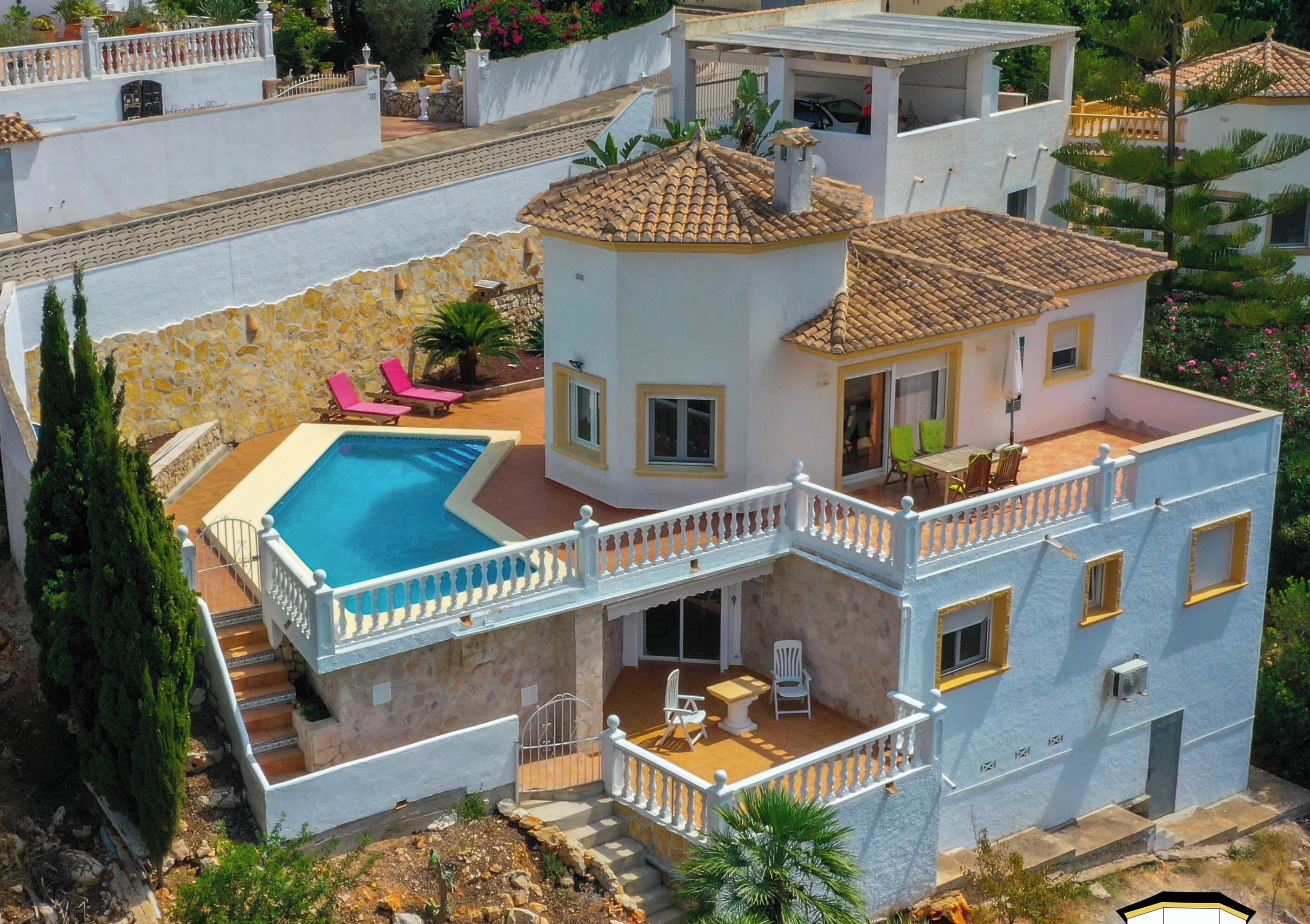 A multi-story house with a swimming pool, balconies, and outdoor seating areas.