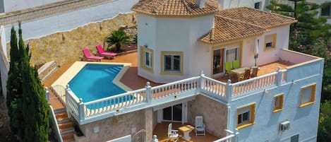 A multi-story house with a swimming pool, balconies, and outdoor seating areas.