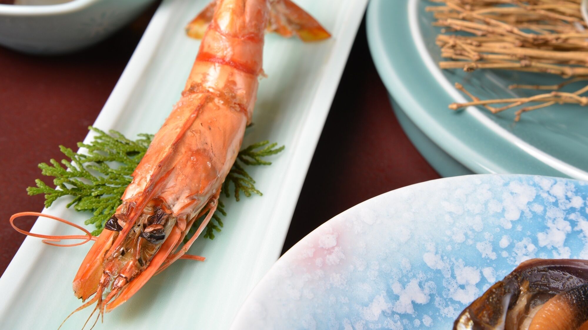 A plate with a cooked shrimp, a plate with a shell, and a plate with a blue pattern.