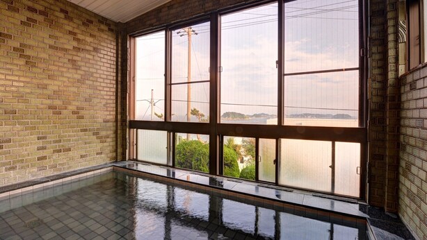 Ein Zimmer mit großem Fenster, Schwimmbad und Backsteinwand.