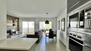 Una cocina moderna con una isla grande, horno empotrado y comedor con sillas y mesa.