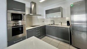 Una cocina moderna con electrodomésticos de acero inoxidable, horno empotrado, microondas, fregadero y refrigerador.