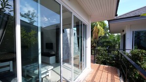 A modern house with large glass sliding doors, a patio with a brick floor, and a white railing. - Yokyor Resort (Sikao)