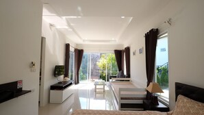A modern hotel room with a bed, a TV, a sofa, and a balcony with curtains. - Yokyor Resort (Sikao)