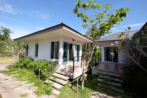 A two-story house with a covered porch and a small garden area. - Yokyor Resort (Sikao)