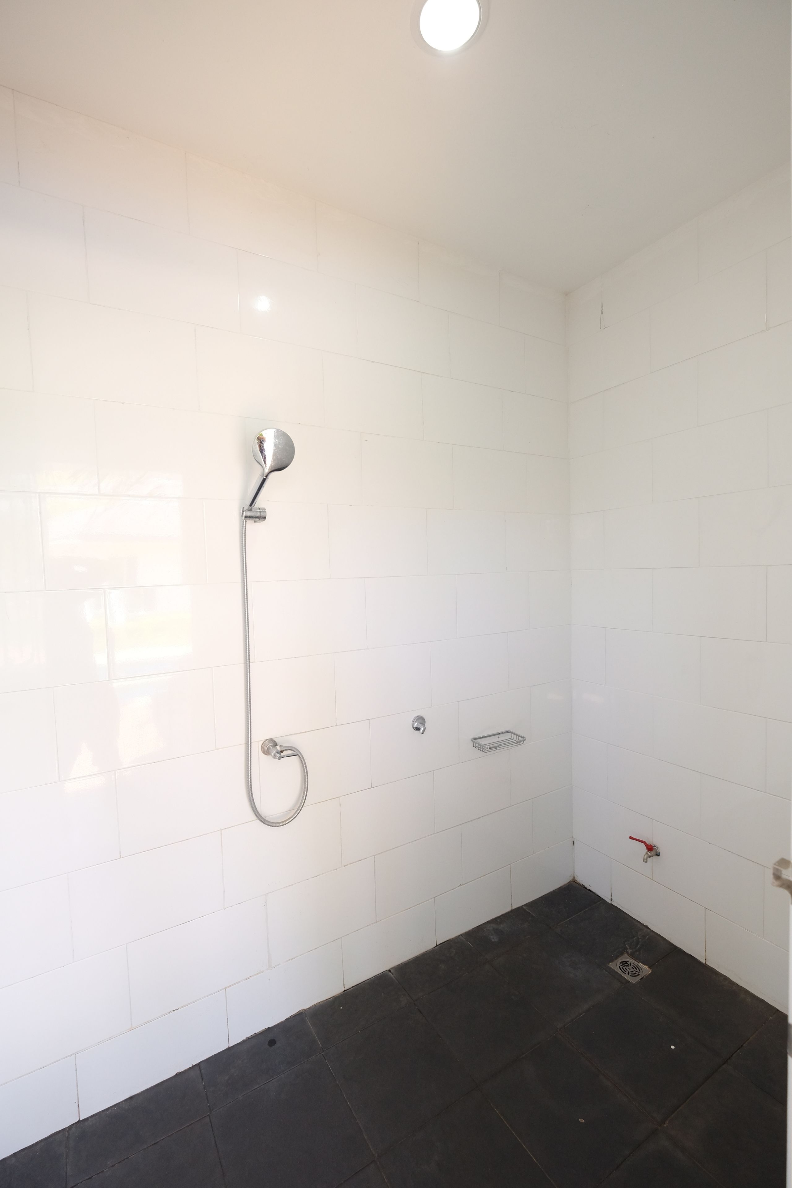 Un baño pequeño con azulejos, ducha, inodoro y lavamanos.