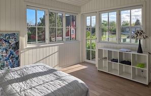A bedroom with a large bed, a white console table, and a window with a view of a red building and greenery.
