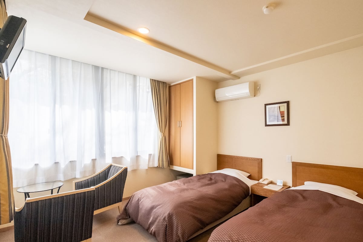 Habitació d'hotel amb un llit, una taula de nit i una cadira a l'escriptori.