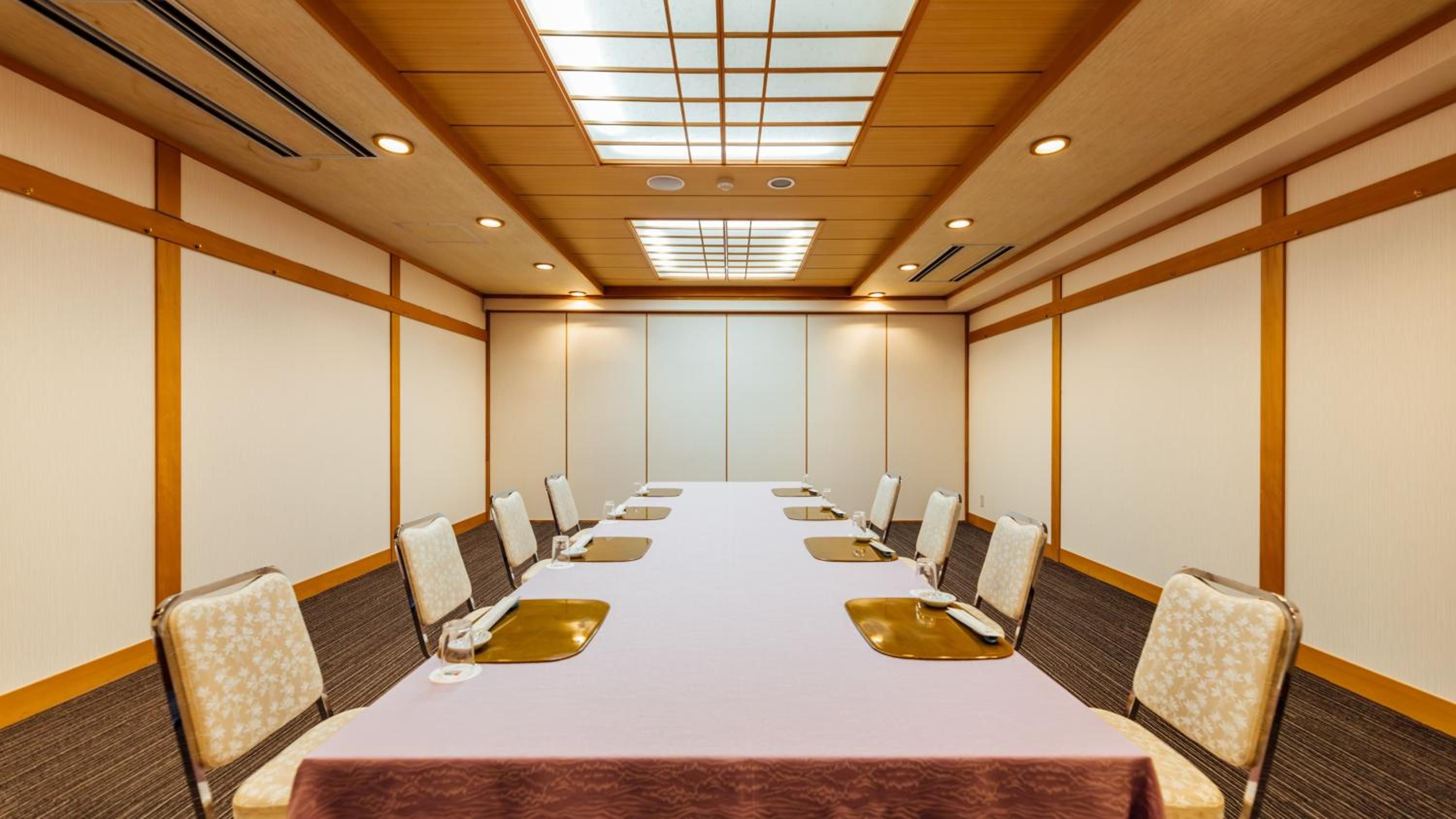 A conference room with a long table, chairs, and a ceiling with recessed lighting.