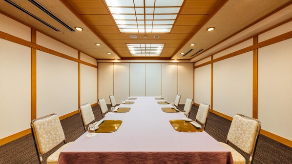 A conference room with a long table, chairs, and a ceiling with recessed lighting. - Urban Hotel (Nihommatsu)