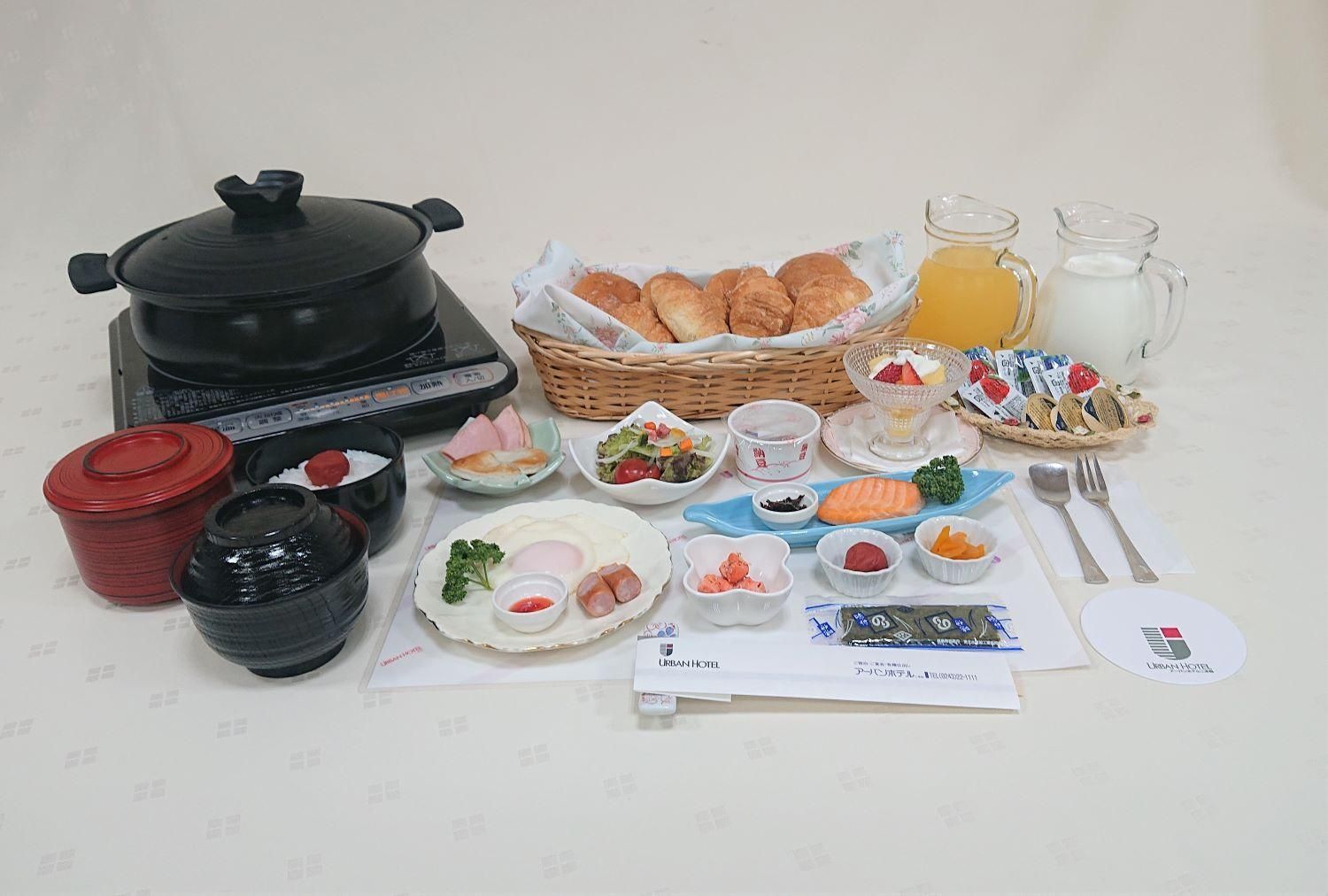 A variety of food items and condiments arranged on a table, including a pot, baskets of bread, and several small dishes with different foods.