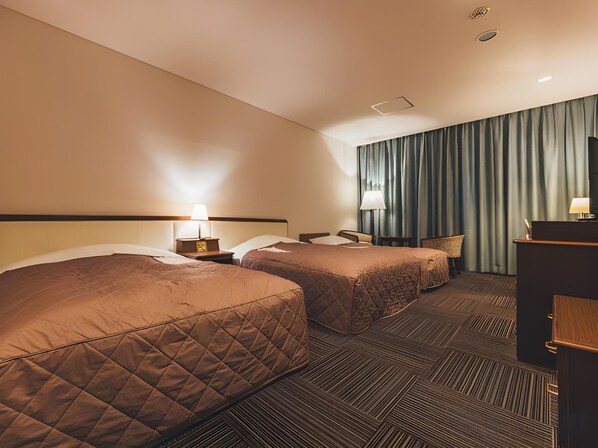 A hotel room with two beds, a desk, a chair, and a large window with curtains. - Urban Hotel (Nihommatsu)