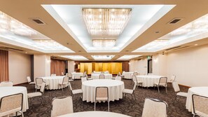 A hotel conference room with round tables, chairs, and a chandelier. - Urban Hotel (Nihommatsu)