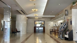 Un vestíbulo de hotel con piso pulido, una recepción y una escalera.