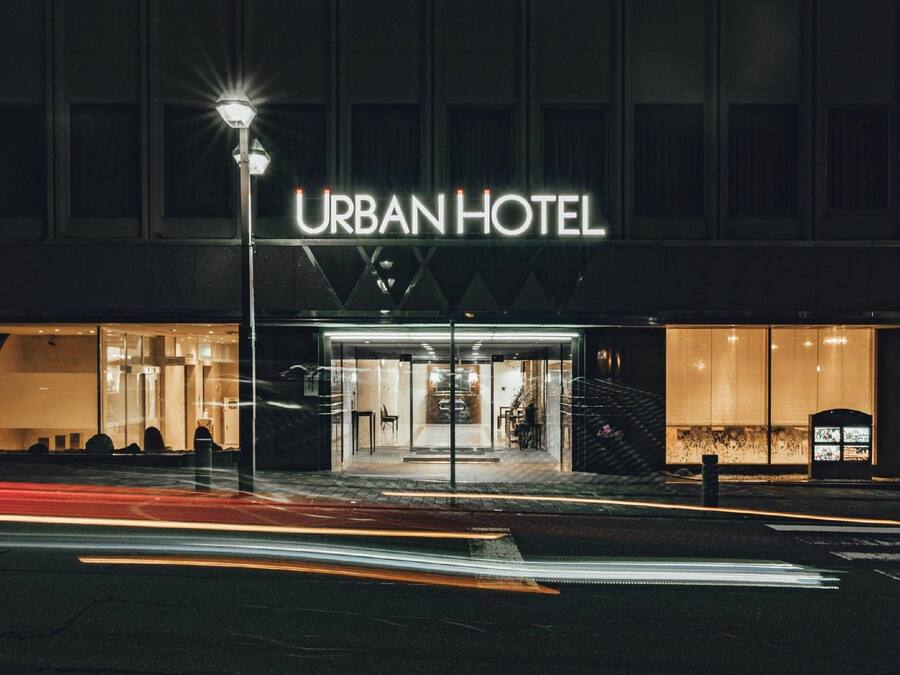 Het uiterlijk van een stadsHotel met een opvallende ingang en een bord waarop 'URBAN HOTEL' staat.