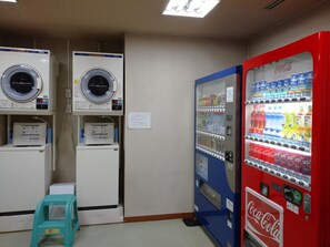 Una lavandería con dos lavadoras y una máquina expendedora de refrescos.