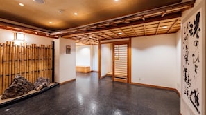 Una habitación espaciosa con piso pulido, un separador de bambú y una puerta corredera tradicional.