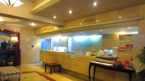 A reception area with a reception desk, a small table, and a potted plant.
