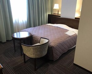 A hotel room with a bed, a chair, a small table, and a lamp. - Urban Hotel (Nihommatsu)