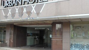 Exterior del Hotel Urban, con fachada moderna, amplio acceso de vidrio y una recepción visible.
