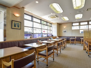 A restaurant interior with booths, tables, and a view of the street through large windows. - Yokkaichi City Hotel Annex (Yokkaichi)