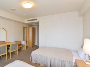 Een hotelkamer met een bed, een bureau met stoel, een spiegel en een nachtkastje met lamp.