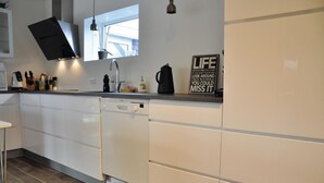A modern kitchen with white cabinets, a dishwasher, a coffee maker, and a sign on the counter. - Lovely home in Otterup with WiFi (Otterup)