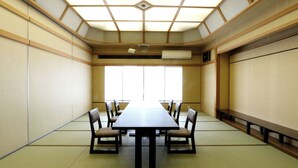 Una sala riunioni in stile tradizionale giapponese, con pavimento in tatami, un tavolo basso e sedie di legno.