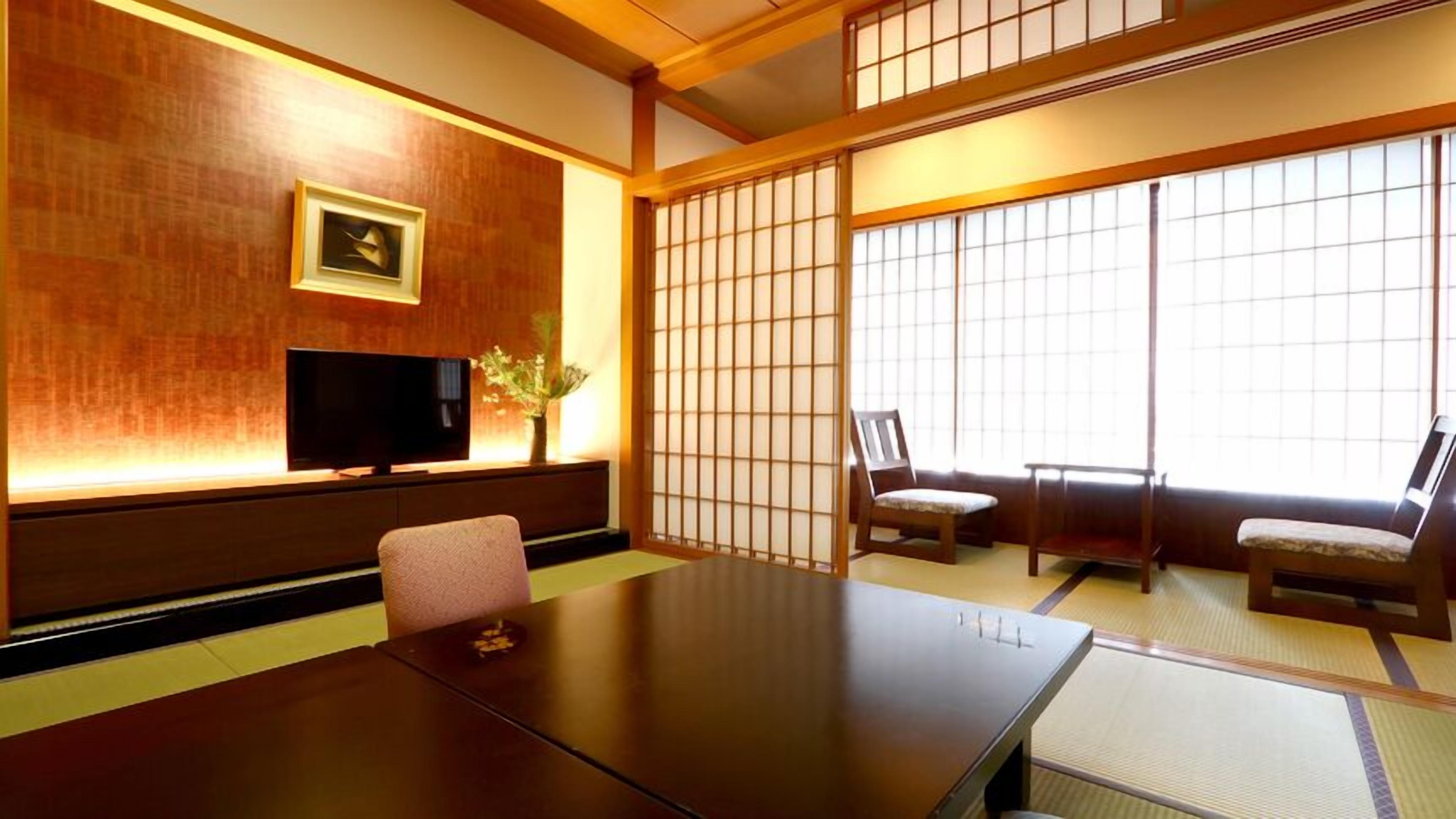 Habitació japonesa tradicional amb sòl de tatami, una taula baixa, dues cadires, un televisor i un panell shoji.
