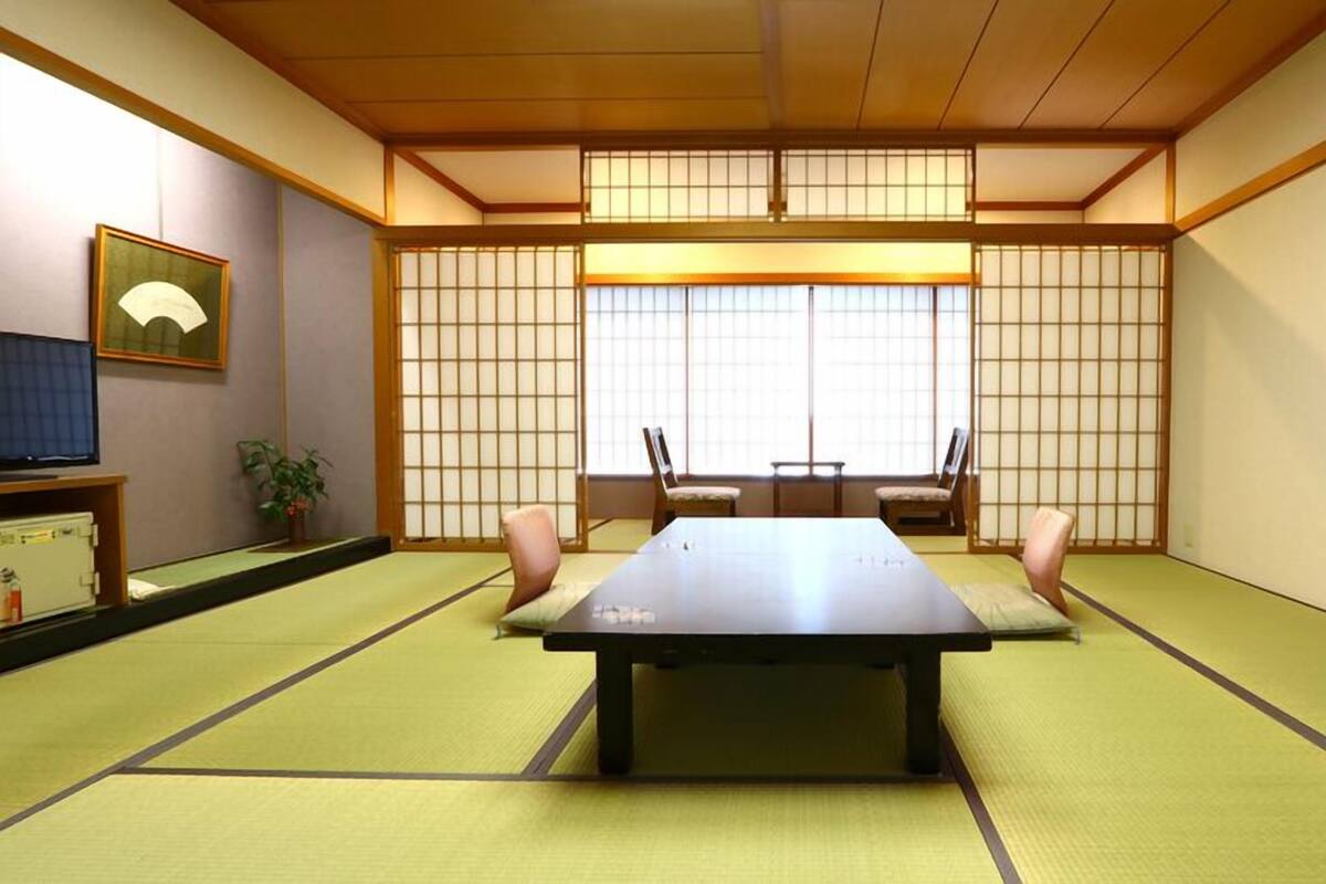 Ein traditioneller japanischer Raum mit Tatami-Boden, einem niedrigen Tisch und verschiebbaren Türen.