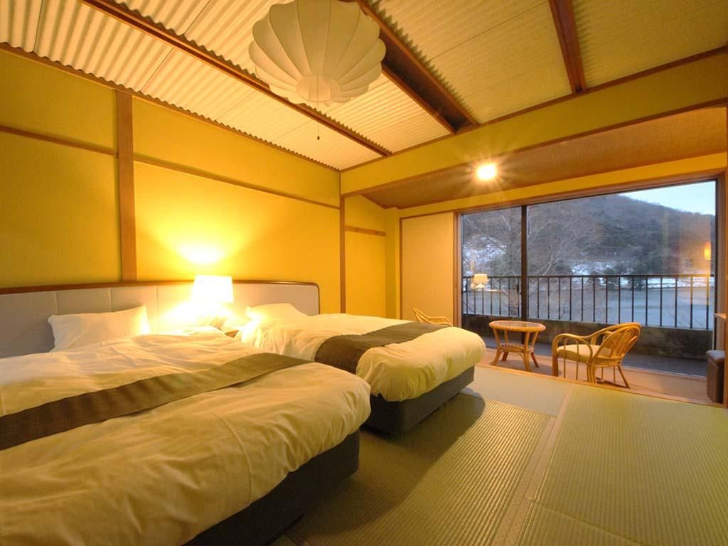 A hotel room with two beds, a sitting area with chairs, a large window, and a view of the outdoors.