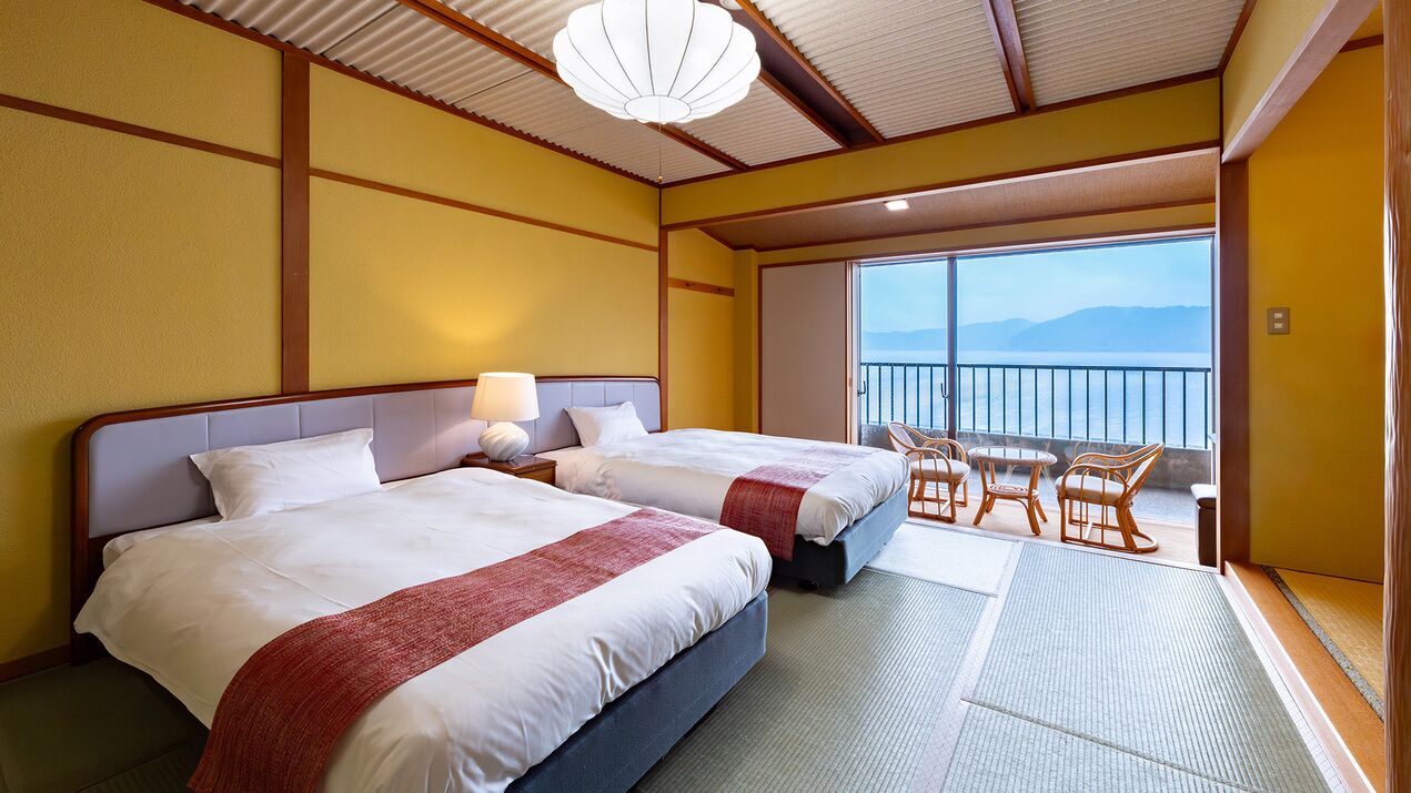 Ein Hotelzimmer mit zwei Betten, einem Balkon mit Sitzgelegenheiten und Blick auf die Berge.