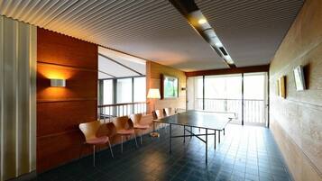 A conference room with a long table and chairs, large windows, and a ceiling with a ribbed design.