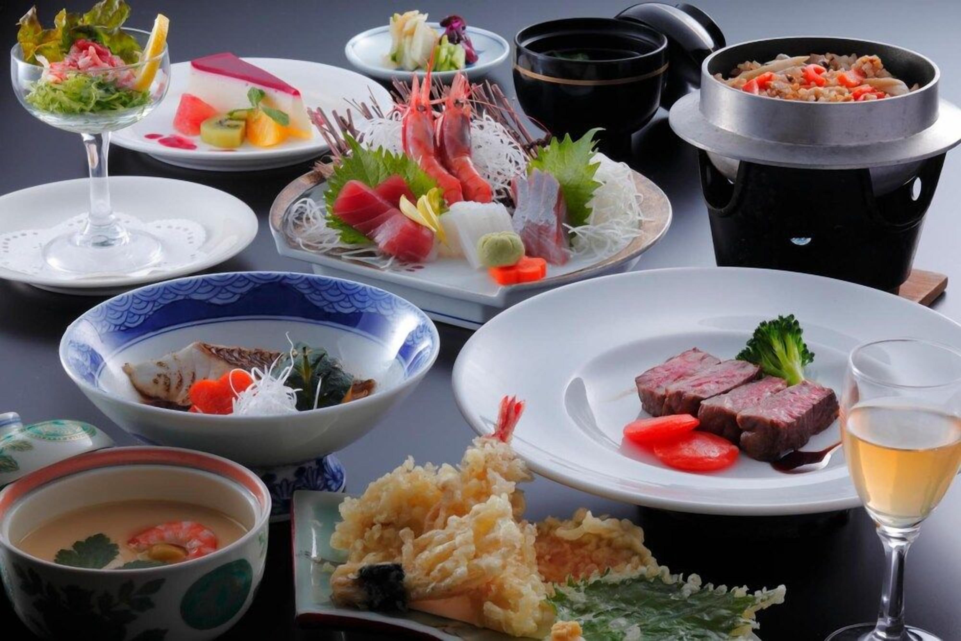A variety of dishes including sashimi, a pot of rice, and a bowl of soup.