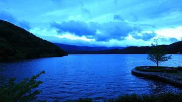 A serene lake surrounded by hills, with a clear sky above.