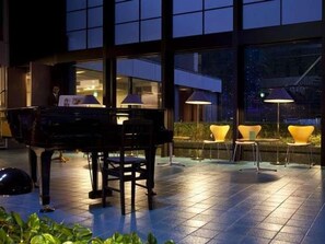A piano in an outdoor area with chairs and tables, large windows, and a view of the city. - Wakasamikata Kirara Onsen Hotel Suigekka (Wakasa)