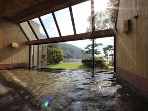 A hot spring room with a wooden interior, a glass enclosure, and a view of a mountainous landscape. - Wakasamikata Kirara Onsen Hotel Suigekka (Wakasa)