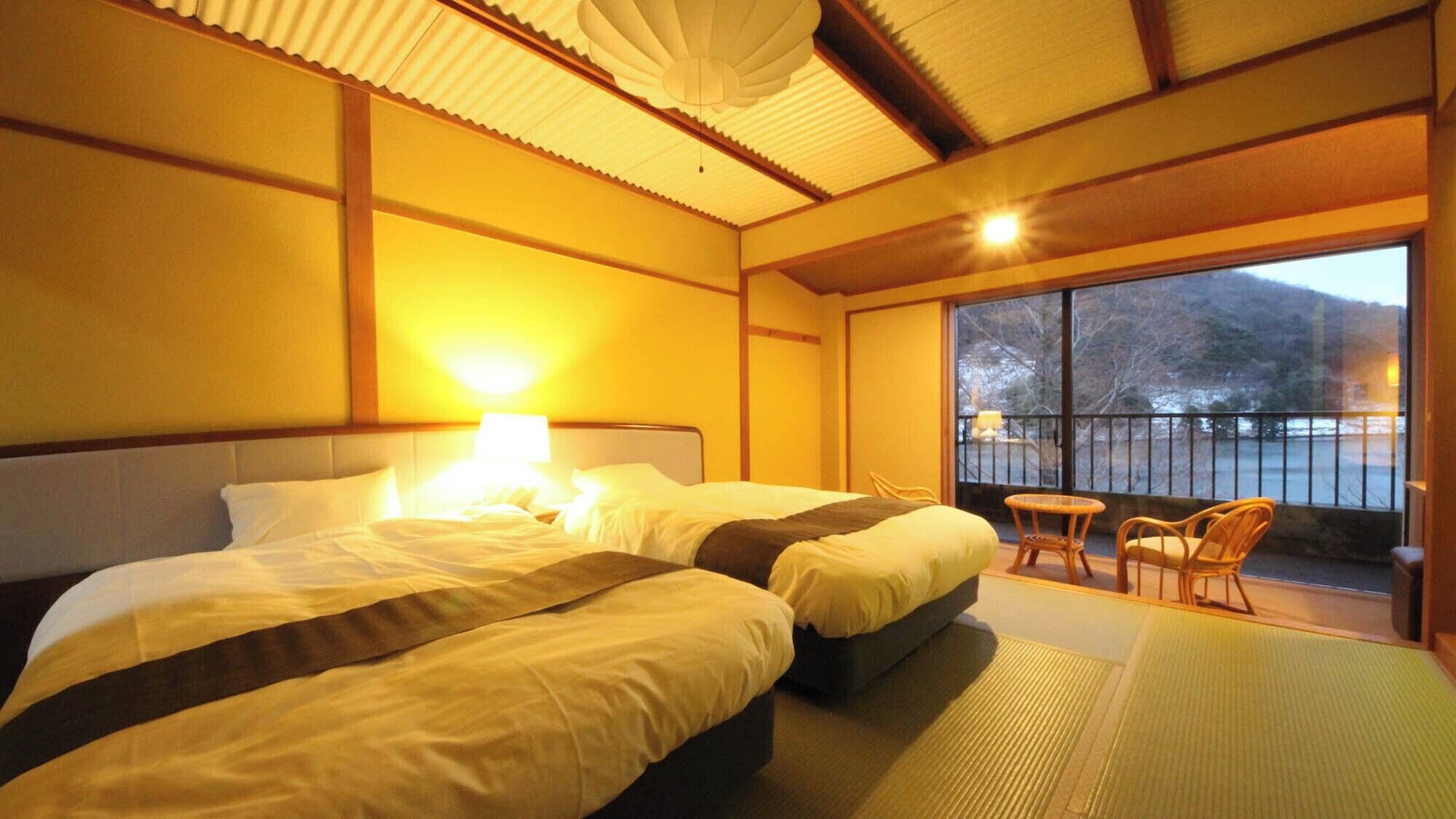 A hotel room with two beds, a balcony with chairs, and a large window.