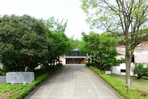 A pathway leading to a building with a modern entrance, surrounded by lush greenery and trees. - Wakasamikata Kirara Onsen Hotel Suigekka (Wakasa)