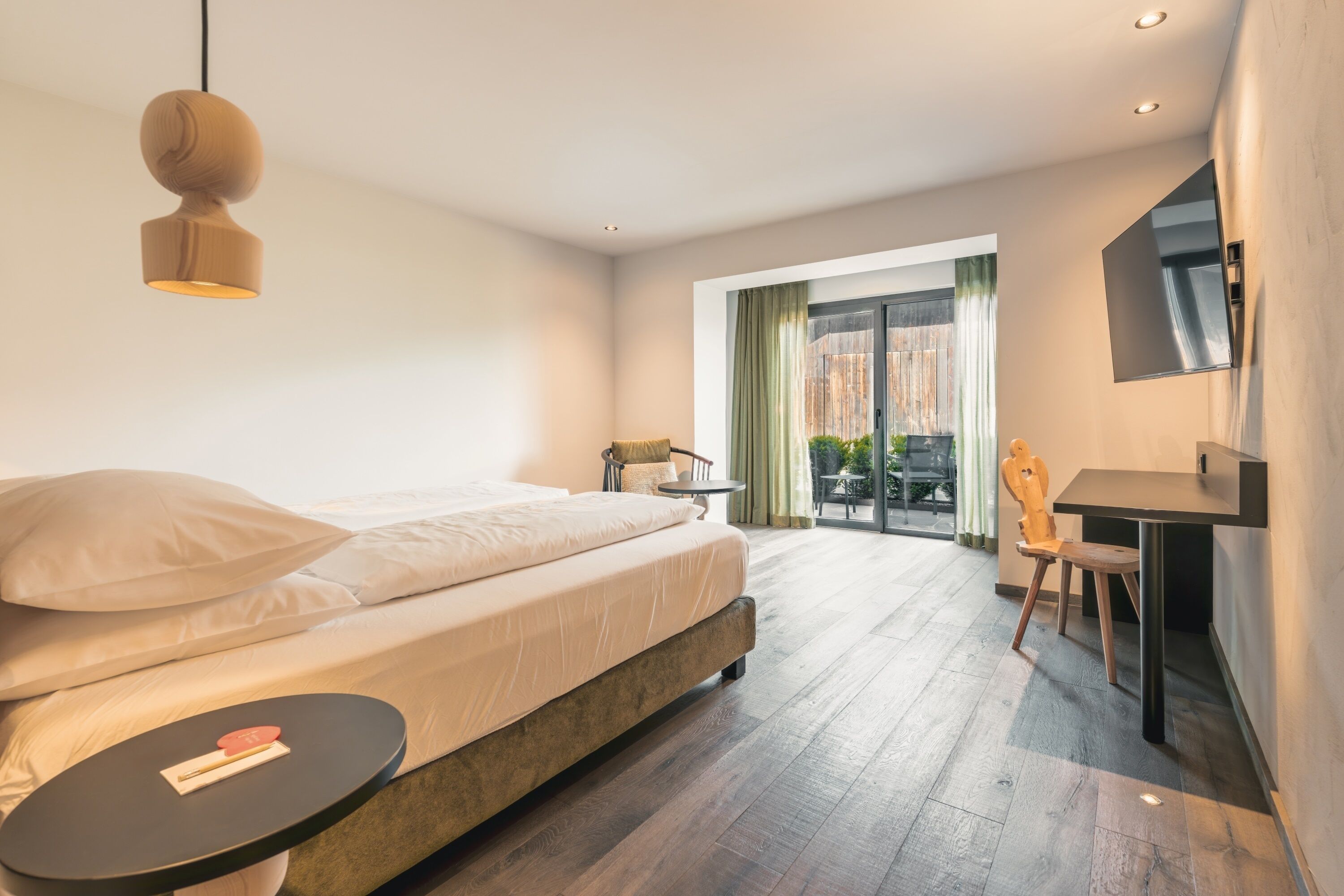 Une chambre moderne avec un lit, une table de chevet et une vue sur l’extérieur.